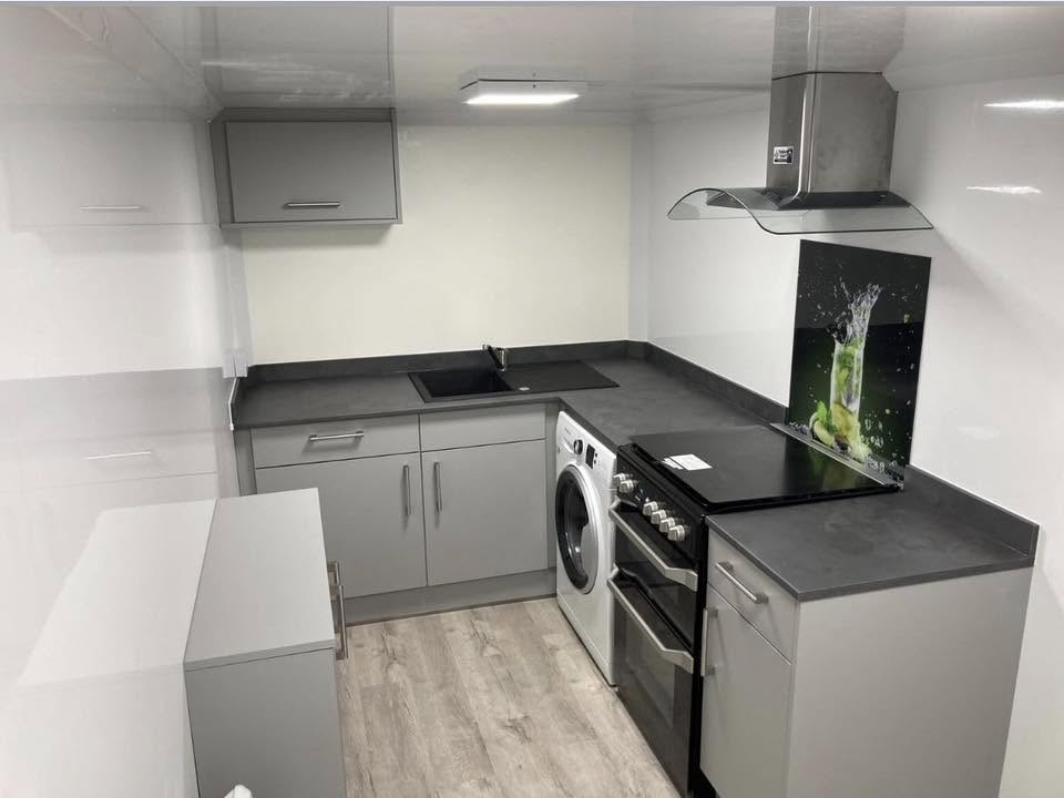 Interior of a temporary kitchen pod with cooker, washing machine and dining area