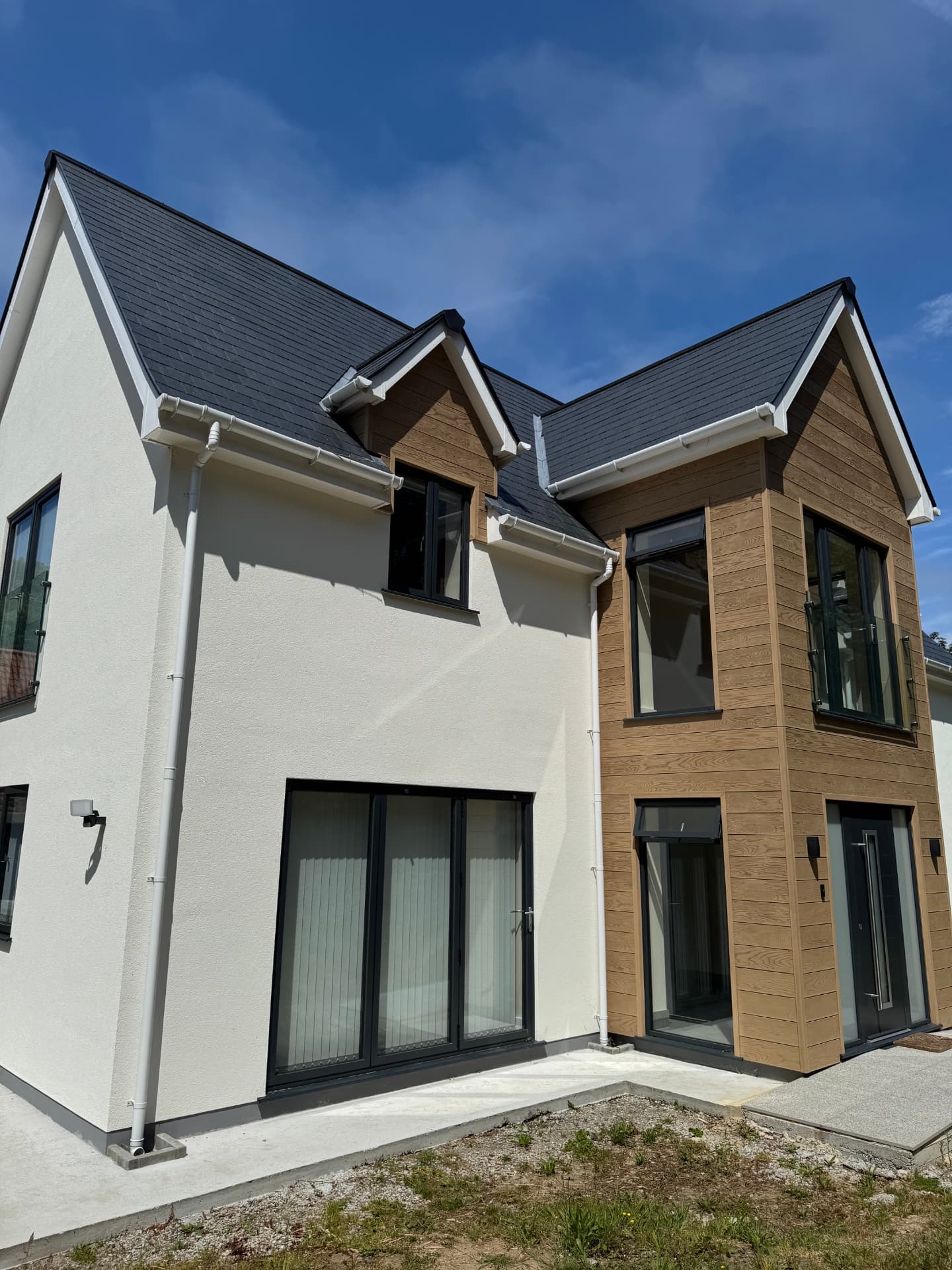 Close view of the timber cladding, glass balustrade and entrance of the newbuild