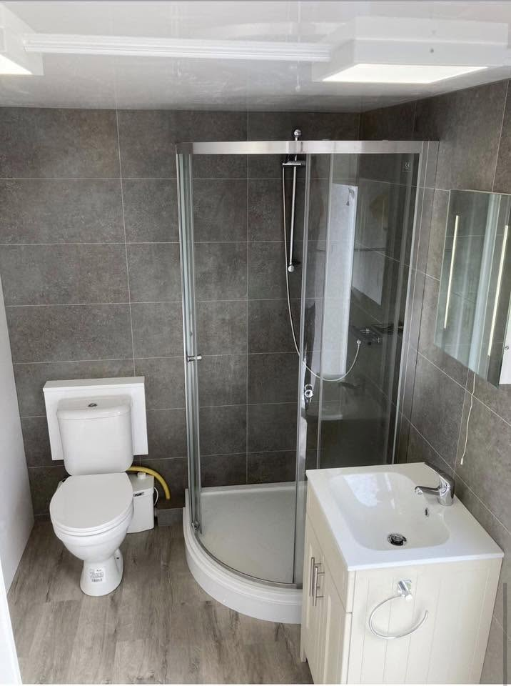 Interior of a temporary shower pod with shower cubicle, toilet and heated towel rail